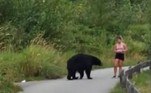 Assim que o urso surgiu de trás das moitas, a jovem não identificada ficou totalmente sem ação