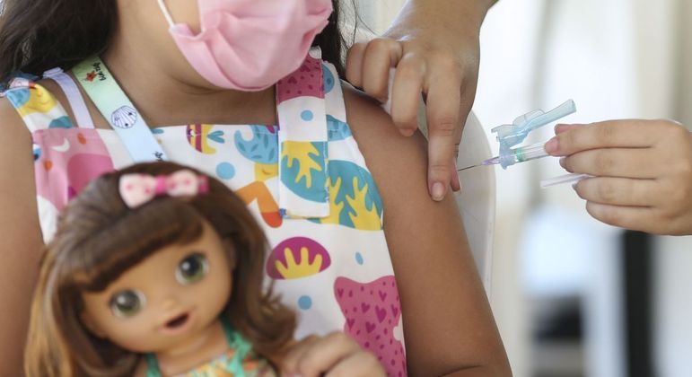 Criança sendo vacinada por uma profissional da saúde