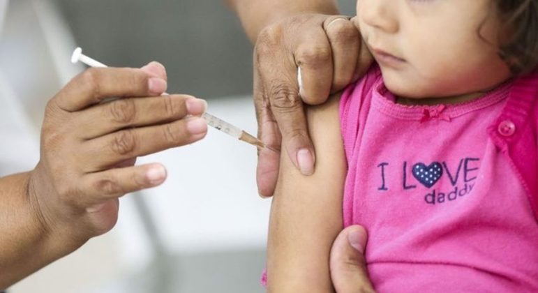 Criança sendo vacinada por uma profissional da saúde 
