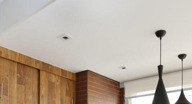 Varanda com churrasqueira de tijolinhos e armários de madeira