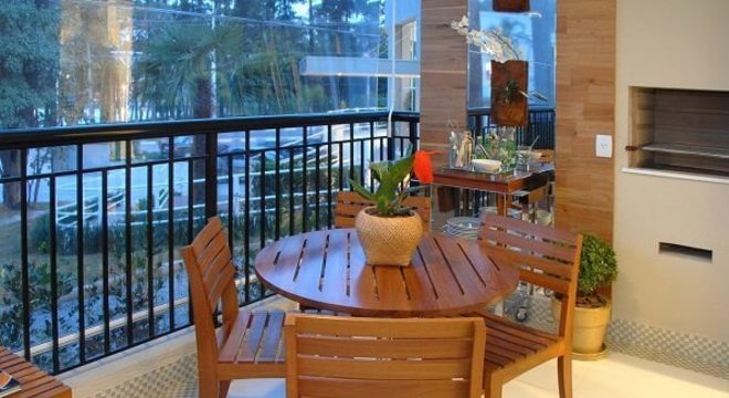 Varanda gourmet com mesa redonda e cadeira de madeira