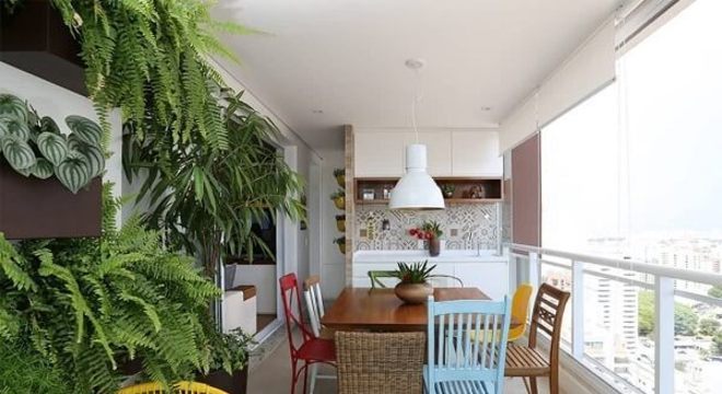 Varanda gourmet decorada com mesa e cadeira de madeira colorida