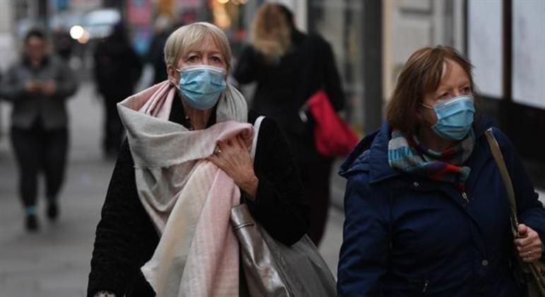 Mulheres usam máscara enquanto caminham em Londres