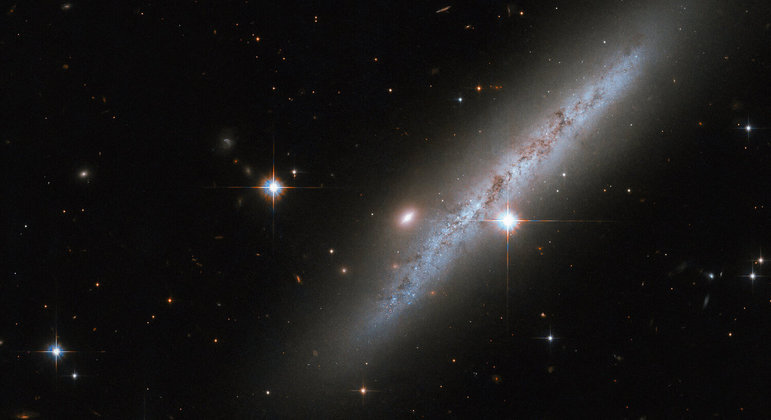O telescópio espacial Hubble registrou a galáxia espiral UGC 2890, que está rodeada de estrelas brilhantes. A galáxia, localizada a 30 milhões de anos-luz da Terra na constelação de Camelopardalis, teve uma explosão de supernova detectada em 2009. Por isso, o telescópio realizou uma 'paradinha' para observar a região e as consequências do evento, mesmo com o desaparecimento da supernova