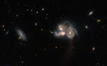 A imagem acima mostra a incrível fusão de três galáxias diferentes, se tornando uma só galáxias. Por estarem na mesma rota de colisão, elas acabaram fundindo e distorceram a estrutura espiral uma da outra, por causa da interação gravitacional mútua durante o processo