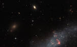 A imagem acima, do icônico Hubble, mostra a pequena galáxia UGCA 307 — ela consiste em uma faixa difusa de estrelas com bolhas vermelhas de gás, que marcam as regiões de formação estelar recente. A galáxia da constelação de Corvus fica a aproximadamente 26 milhões de anos-luz da Terra