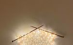 Criatividade sem limites: duas agulhas de tricô + apenas um pedaço da trama + luzinhas de Natal são o suficiente para criar uma luminária sem igual para enfeitar as paredes e iluminar o cômodo