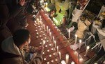 Manifestantes se reúnem ao longo de uma rua com velas e buquês de flores em Pequim