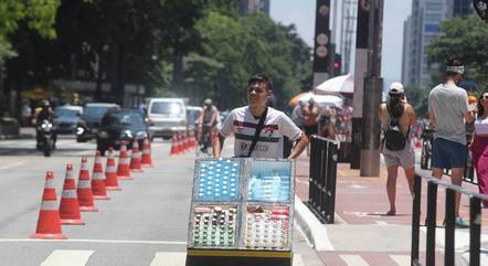 Vendedor ambulante empurra carrinho com garrafas de água na Av. Paulista