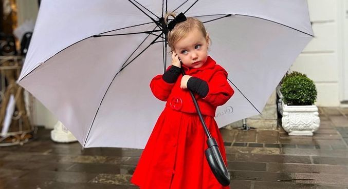 Vicky roubou a cena com vestido vermelho, botas pretas e laço no cabelo