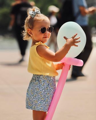 Durante a viagem, Vicky também apareceu com um visual marcado por lacinhos, que estavam presentes tanto na regatinha como no acessório do cabelo. Mais uma vez, a estampa de flores também compôs o figurino - desta vez, no shortinho 