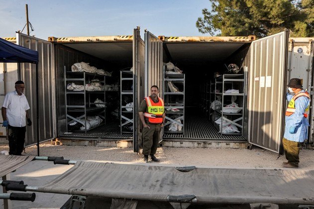 Um soldado do Exército israelense abre um contêiner refrigerado que foi convertido em uma área de armazenamento improvisada para os corpos das vítimas mortas durante os ataques do Hamas na Faixa de Gaza 