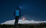 Homem observa de longe a erupção do Etna