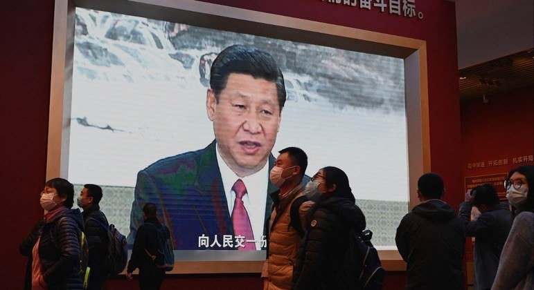 Visitantes caminham em frente a uma imagem de Xi Jinping, no Museu do Partido Comunista